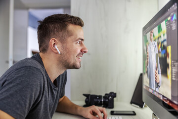 Fototapeta premium A professional photographer and graphic designer carefully observe every detail in the photo he edited, proud of his work. Creative industry, work from home, freelance, love my job