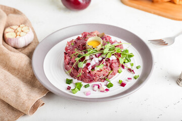 Plate with tasty beef tartare on light background