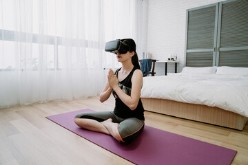 chinese lady in dark color outfit is doing yoga with aid of vr technology for deep immersion. asian...