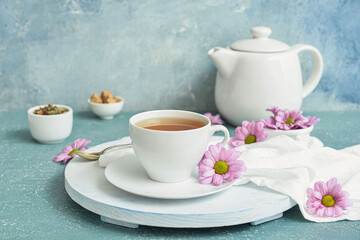 Cup with tasty floral tea on color background