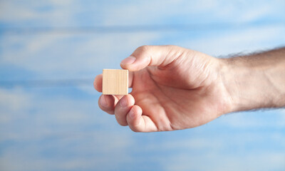 Male hand holding wooden empty cube.