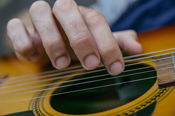 Fototapeta premium close-up of a guitar playing with the fingers of a man's hand playing the strings