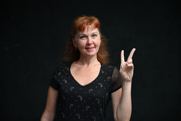 Red-haired caucasian woman showing her fingers with a smile in the studio on a black background