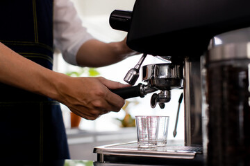 Close up hand. Making a cup of coffee in a coffee machine, the steam and the cup. Espresso maker machine with portafilter close up. Concept Coffee maker in cafe.