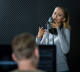 Teen female singer woking in voice studio with intention and happiness, she wears headphones...