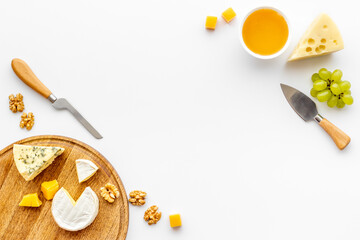 Set of cheese on wooden board with cheese knives, top view