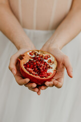 Girl in a dress holds a pomegranate in her hands