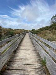 Fototapeta na wymiar Wooden path over the dunes at Le Touquet, France. The path leads to observatory of the Canche walk