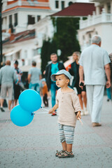 a 2-3-year-old boy walks with blue balloons in his hands