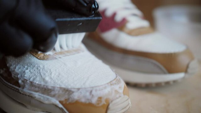 Worker cleaning sneakers with brush and professional cleaning stuff in shoes workshop. Sneaker Cleaning Service. Top view.