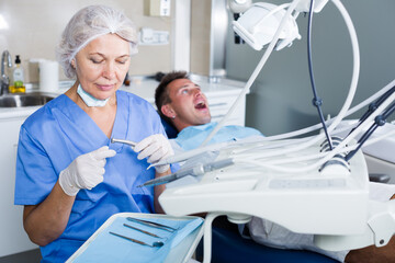 Confident female dentist in dental office with male patient in chair