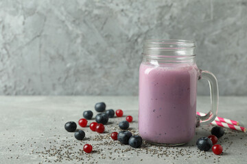 Glass jar of smoothie, ingredients and straws on gray textured table