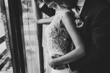 The bride and groom. First meeting. Newlyweds standing indoors near window. Black and white photo.