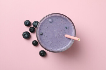 Glass of blueberry smoothie on pink background