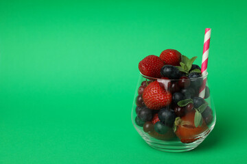 Glass with smoothie ingredients on green background