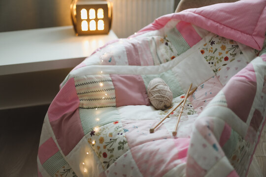 Cozy homely background with wool yarn and knitting needles on an armchair with a blanket.