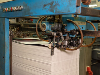 Machine in printing house folding papers with rollers on a conveyor belt