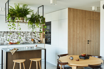 Stylish kitchen interior design with dining space. Workspace with kitchen accessories on the back ground. Creative walls with woode pannels. Minimalistic style an plant love concept.