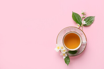 Cup of jasmine tea and flowers on color background
