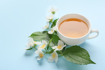 Cup of jasmine tea and flowers on color background