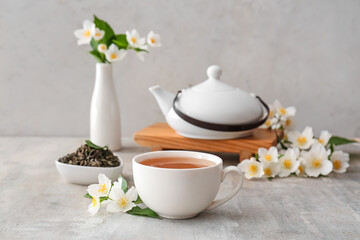 Composition with cup of jasmine tea and flowers on grunge background
