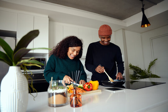 Young Mixed Race Couple Cooking Food In The Kitchen At Home. Couple Preparing Food. High Quality Photo 