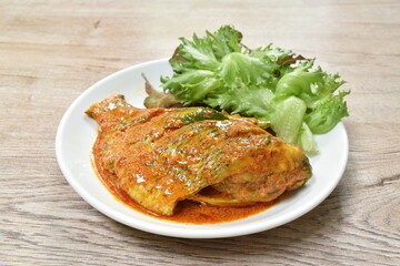 steamed mango fish dressing spicy coconut milk curry sauce on plate