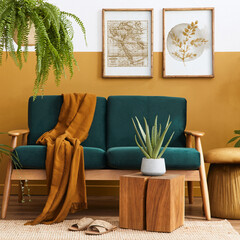 Stylish scandinavian interior of living room with design green velvet sofa, gold pouf, wooden furniture, plants, carpet, cube and mock up poster frames. Template.
