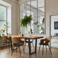 Stylish and cozy interior of dining room with design craft wooden table, chairs, plants, velvet sofa, poster map and elegant accessories in modern home decor. Template.