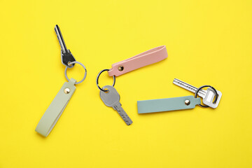Keys with leather keychains on color background