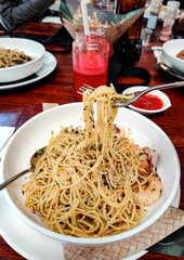 A large serving of a plate of delicious aglio olio with seafood and grated cheese. Blurred background