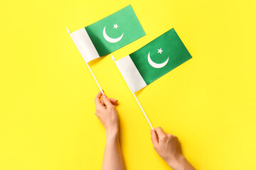 Female hands with Pakistan flags on color background