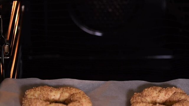 Baker puts their Turkish bagel simit buns in the oven.