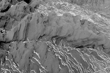 Layered black stone with wavy white stripes, texture close-up