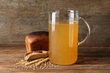 Jug of fresh kvass on wooden background