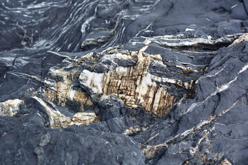 Natural abstraction texture of black stone with splashes, close-up