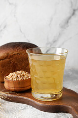 Glass of fresh kvass on light background