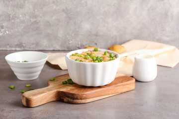 Ramekin with tasty potato casserole on grunge background