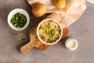 Ramekin with tasty potato casserole on grunge background