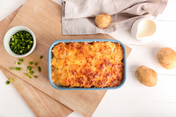 Baking dish with tasty potato casserole on light background