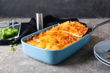 Baking dish with tasty potato casserole on grunge background, closeup