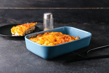 Baking dish with tasty potato casserole on dark background