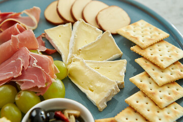 On a plate, crackers, ham, cheese, olives,