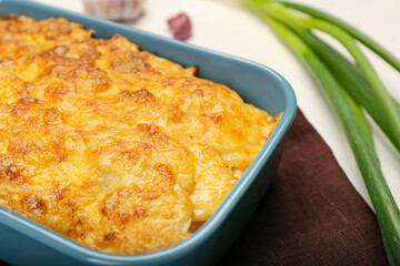 Baking dish with tasty potato casserole on light background, closeup