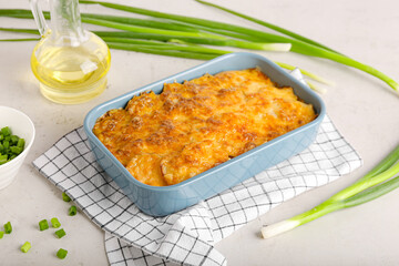 Baking dish with tasty potato casserole on light background