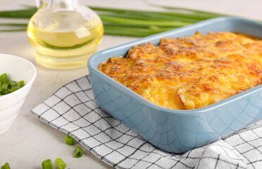 Baking dish with tasty potato casserole on light background, closeup