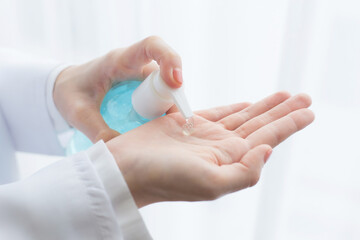 Asian professional female doctor sat using alcohol gel to wash her hands while waiting for the disease examination.