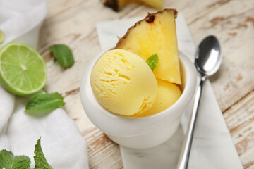 Bowl with tasty pineapple ice cream and lime on light wooden background, closeup