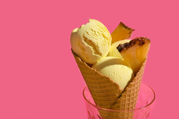 Glass with tasty pineapple ice cream in wafer cone on color background, closeup