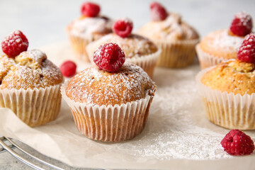 Grid with tasty raspberry muffins on table, closeup